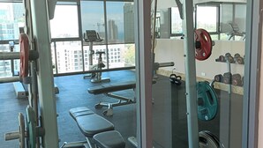 A gym with exercise equipment, benches, and weights. - Peaceful SEA View Condo (Pattaya)