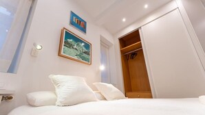 Camera da letto con un letto, cuscini, un quadro incorniciato, un armadio e una lampada a soffitto.