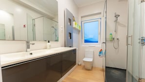 Un bagno moderno con cabina doccia in vetro, uno specchio grande e un water.