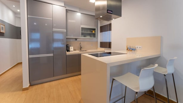 Una cucina moderna con elettrodomestici in acciaio inossidabile, un'isola centrale con sgabelli da bar e un forno integrato.