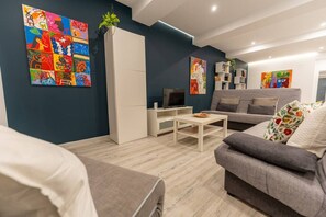 Un saló modern amb un sofà gris, una taula de cafè blanca i obra d'art abstracta i colorida a les parets.
