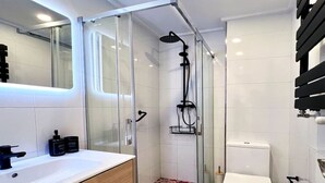 A modern bathroom with a glass-enclosed shower, a white toilet, and a wooden vanity with a sink. - 3 rooms apartment close beach (Santander)