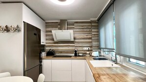 A modern kitchen with white cabinets, a wooden countertop, and a built-in stove. - 3 rooms apartment close beach (Santander)