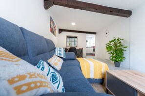 Un salon moderne avec un canapé bleu, des coussins à motifs, une table basse en bois et une plante en pot.