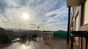 Una terrazza sul tetto con vista sulla campagna, un tavolo con sedie e un recinto verde.