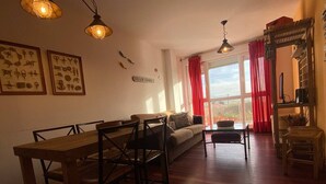 Un accogliente soggiorno con un tavolo da pranzo in legno e sedie, un divano e una tenda rossa.