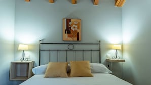 Una cama bien hecha con dos almohadas, un cabecero de metal y dos mesitas de noche con lámparas.