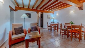 A cozy living area with a wooden ceiling, a dining table with chairs, and a sofa with cushions. - Posada La Canal · Habitación privada posada rural (Ubiarco)