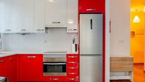 Una cucina moderna con mobili rossi, un frigorifero in acciaio inossidabile e un forno.