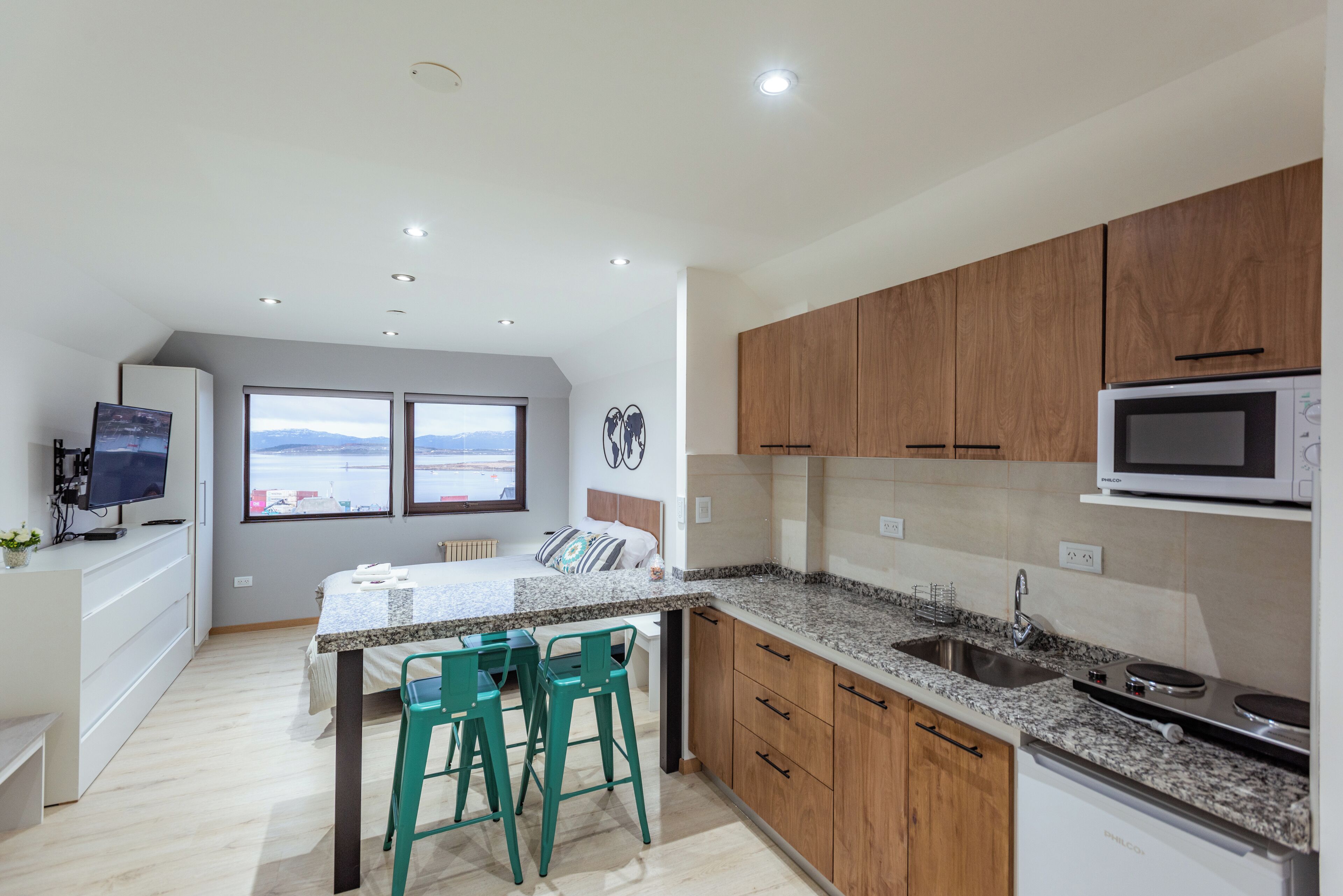 A modern kitchen with wooden cabinets, a granite countertop, and a built-in microwave.