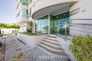 Un bâtiment moderne doté d’une entrée en verre, d’un escalier extérieur et d’un chemin piétonnier dallé.