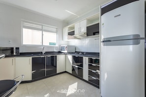 Eine moderne Küche mit weißen Schränken, einer schwarzen Arbeitsplatte und einem Edelstahl-Kühlschrank.