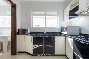 Une cuisine moderne avec des meubles blancs, un plan de travail noir, un four à micro-ondes et un évier.