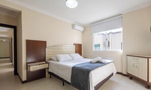 Una habitación de hotel con cama, mesita de noche, armario y ventana con vistas.