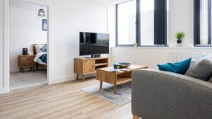 A modern living room with a flat-screen TV, a wooden coffee table, and a grey sofa. - Luxurious Stylish Apartment (Stretford)
