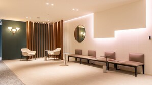 A modern waiting area with a seating arrangement, a round mirror, and a wall-mounted light fixture. - Daplace - Vico Apartment (Milano)