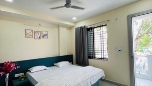 Ein Schlafzimmer mit Bett, Deckenventilator, einem Fenster mit Vorhängen und einer Tür zu einem Außenbereich.