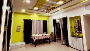 Ein geräumiges Zimmer mit Esstisch, Deckenventilator und Küchenzeile mit Schränken.