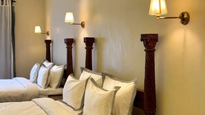 Camera d'albergo con due letti, ciascuno con lenzuola bianche e numerosi cuscini. Ai lati dei letti sono presenti lampade a parete.