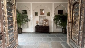 Un interno tradizionale con porte decorate, pavimento in pietra e piante in vaso.
