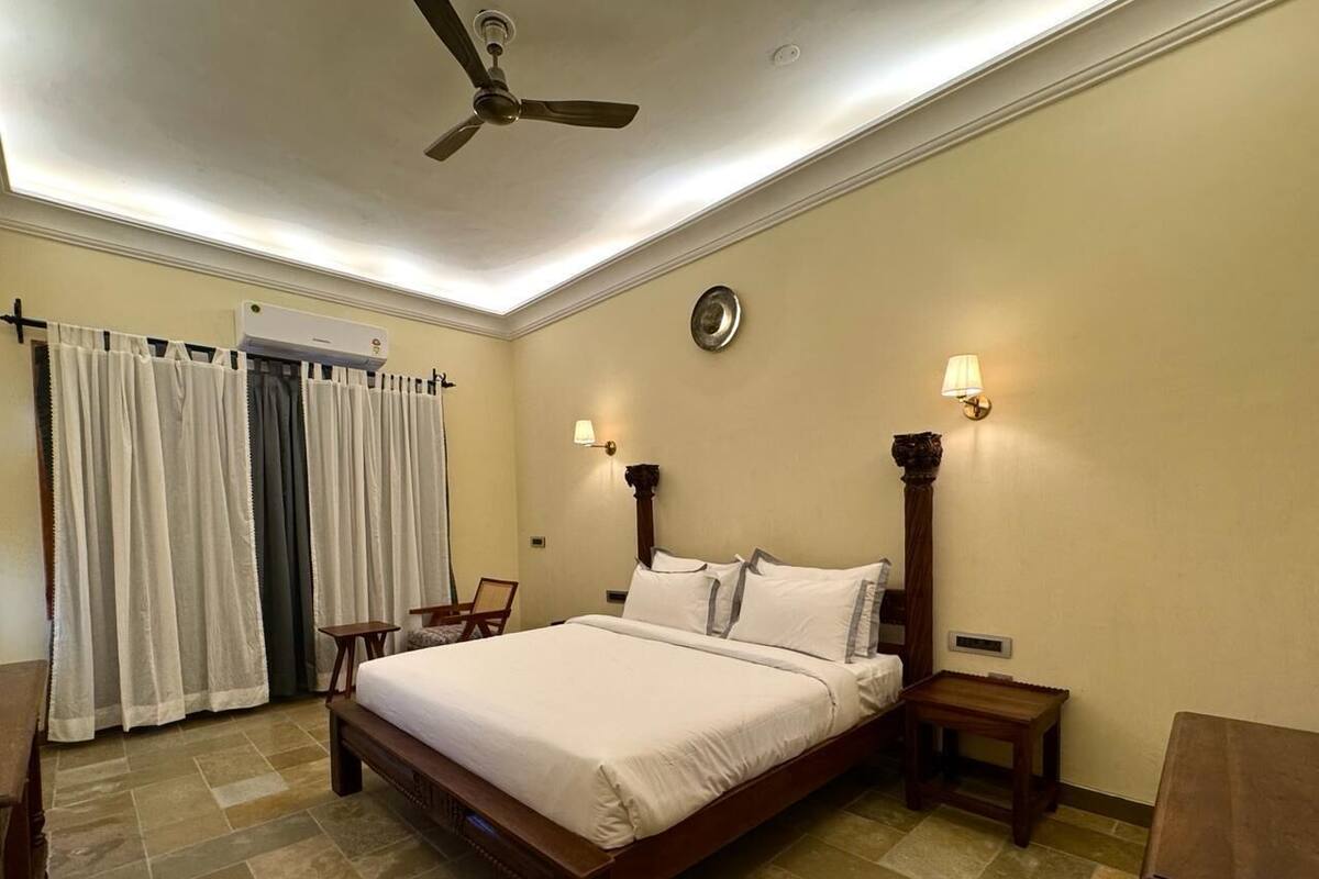 A bedroom with a bed, bedside tables, a ceiling fan, and a wall-mounted air conditioner.