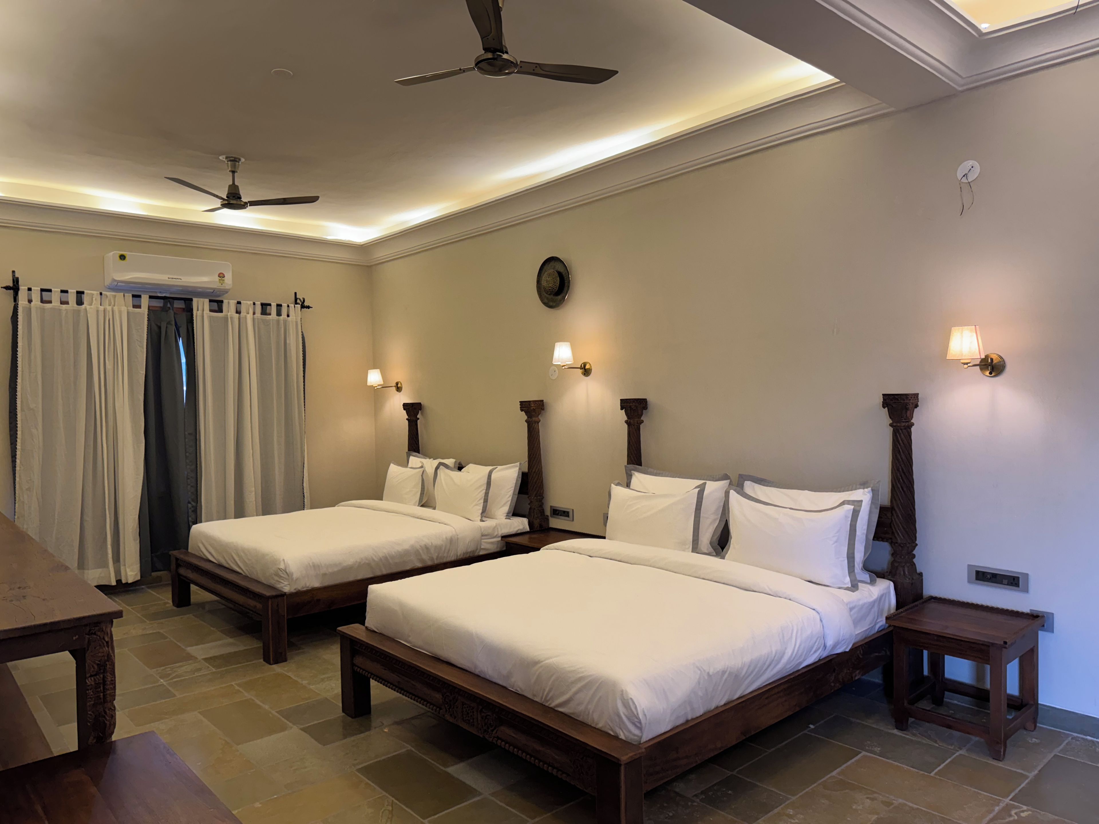 A hotel room with two beds, a ceiling fan, a clock, and a nightstand.