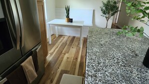 A modern kitchen with a stainless steel refrigerator, wooden cabinets, a white dining table, and a granite countertop. - Adorable 3-bedroom 2-bath House in quiet, safe, kid/pet friendly neighborhood. (Enfield)