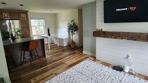 A modern kitchen with wooden cabinets, a stainless steel refrigerator, and a dining area with a table and chairs. - Adorable 3-bedroom 2-bath House in quiet, safe, kid/pet friendly neighborhood. (Enfield)