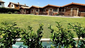 A row of wooden cabins with a grassy lawn in the foreground. - Pto calderon home beach garden (Ubiarco)