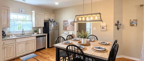 Una cocina moderna con armarios de madera, un refrigerador de acero inoxidable y un comedor con mesa y sillas de madera.