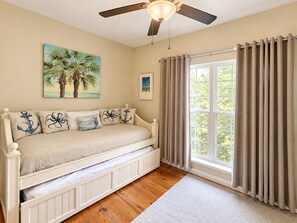A bedroom with a bed, a ceiling fan, a window with curtains, and artwork on the wall. - Whispering Pines Cottage–Peaceful Fort Morgan Retreat | Pool | Close to Beach (Gulf Shores)