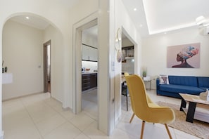 Ein modernes Interieur mit Essbereich, einer Couch und einer durch einen offenen Durchgang einsehbarer Küche.