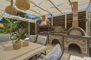 Un patio exterior con chimenea de piedra, asientos y una mesa con cestas tejidas.