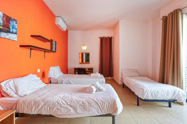 A hotel room with three beds, a desk, a chair, and a mirror. - Roulette Your St Julian s Base for a Fun Getaway (St. Julian's)