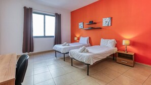 A hotel room with two beds, a desk, a chair, a window with curtains, and artwork on the wall. - Roulette Your St Julian s Base for a Fun Getaway (St. Julian's)
