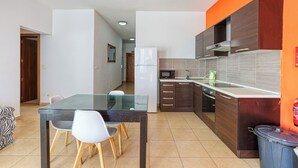 A modern kitchen with dark wooden cabinets, a glass dining table, and white chairs. - Roulette Your St Julian s Base for a Fun Getaway (St. Julian's)