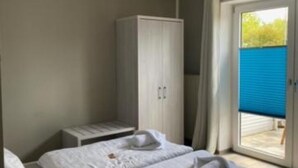 Un dormitorio con cama, armario y ventana con vistas al exterior.