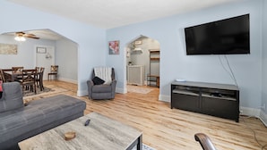 Un salon moderne avec un canapé gris, une table basse en bois et un t éléviseur à écran plat fixé au mur.