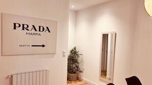 Moderni hotellihuone, jossa on Pradan logo, patteri, ruukkukasvi ja peili.