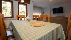 Un coin repas avec une table mise pour deux personnes, une chaise en bois, un set de table en fibres tressées et un bocal en verre posé sur la table.