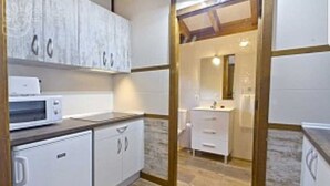 Una cucina compatta con mobili bianchi, un forno a microonde e un lavandino.