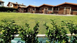 Filetta di cabine di legno con un prato curato e una piscina in primo piano.