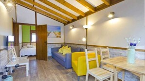 Una stanza accogliente con un letto, un divano blu con cuscini gialli, un tavolo da pranzo in legno e un vaso con fiori.