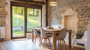 A dining area with a stone wall, a wooden table, and chairs. - The Stone House – naturaleza y confort (villacarriedo)