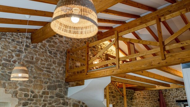 A rustic interior with exposed wooden beams, stone walls, and hanging woven light fixtures. - The Stone House – naturaleza y confort (villacarriedo)