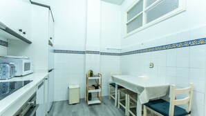 A compact kitchen with white cabinets, a microwave, a small refrigerator, and a dining table with chairs. - Your Bright Retreat in the Heart of Santander (Santander)