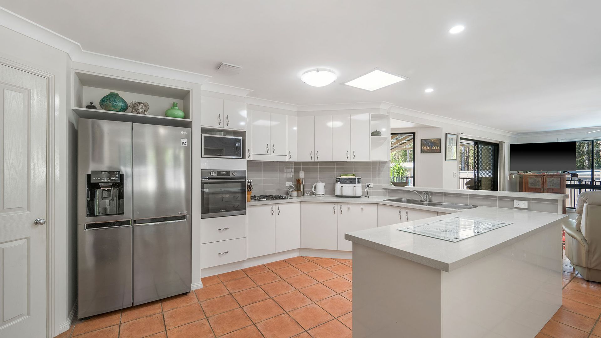 A modern kitchen with white cabinetry, stainless steel appliances, and a large island.