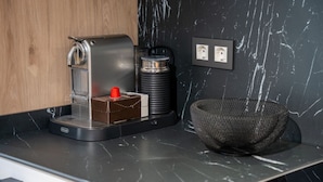 Eine moderne Küche mit einer Kaffeemaschine, einem Wasserkocher und einem Korb auf der Arbeitsfläche.
