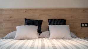 Ein Bett mit gestreifter Bettwäsche, zwei Kissen und ein hölzernes Kopfteil.