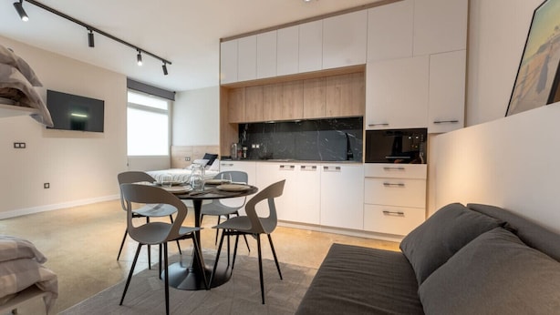Ein modernes, kompaktes Wohnzimmer mit Essbereich, Küchenzeile und einer Couch.